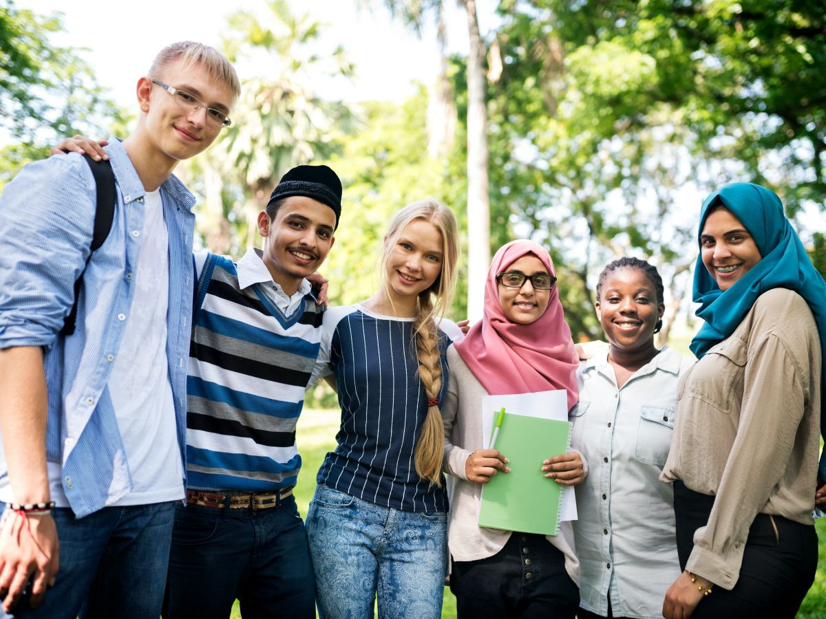 A group of six students standing together outdoors, smiling